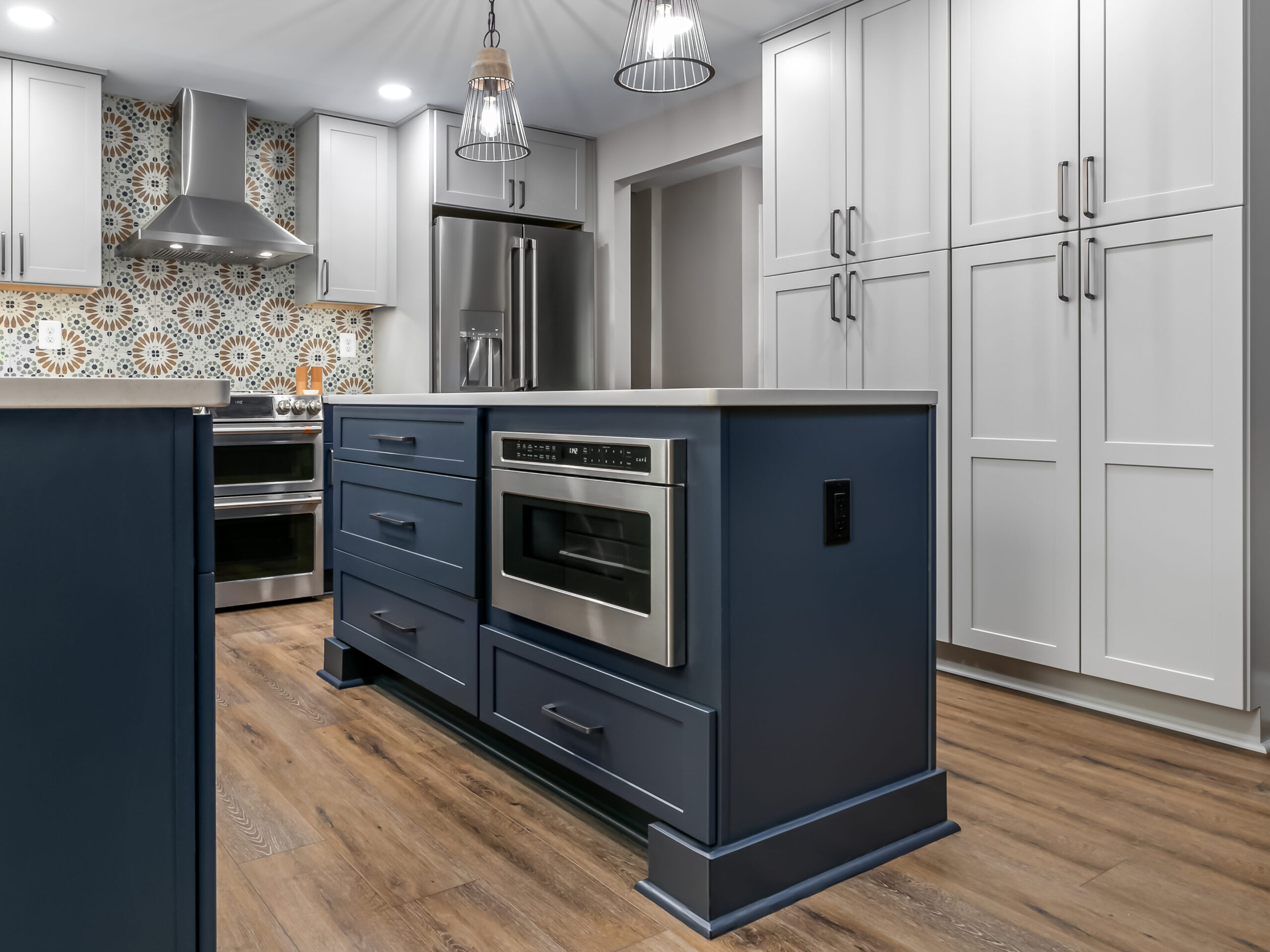 Two-tone kitchen with white shaker perimeter cabinets and a deep indigo island