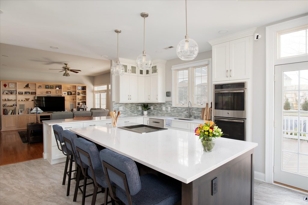 Graphite-stained maple kitchen island with quartz top, four upholstered counter stools, and an integrated electric cooktop