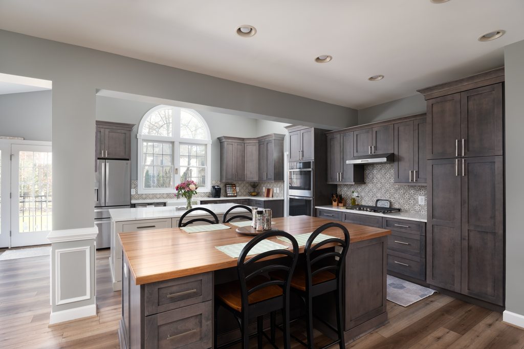 Painted gray prep island with a quartz top and an integrated dishwasher