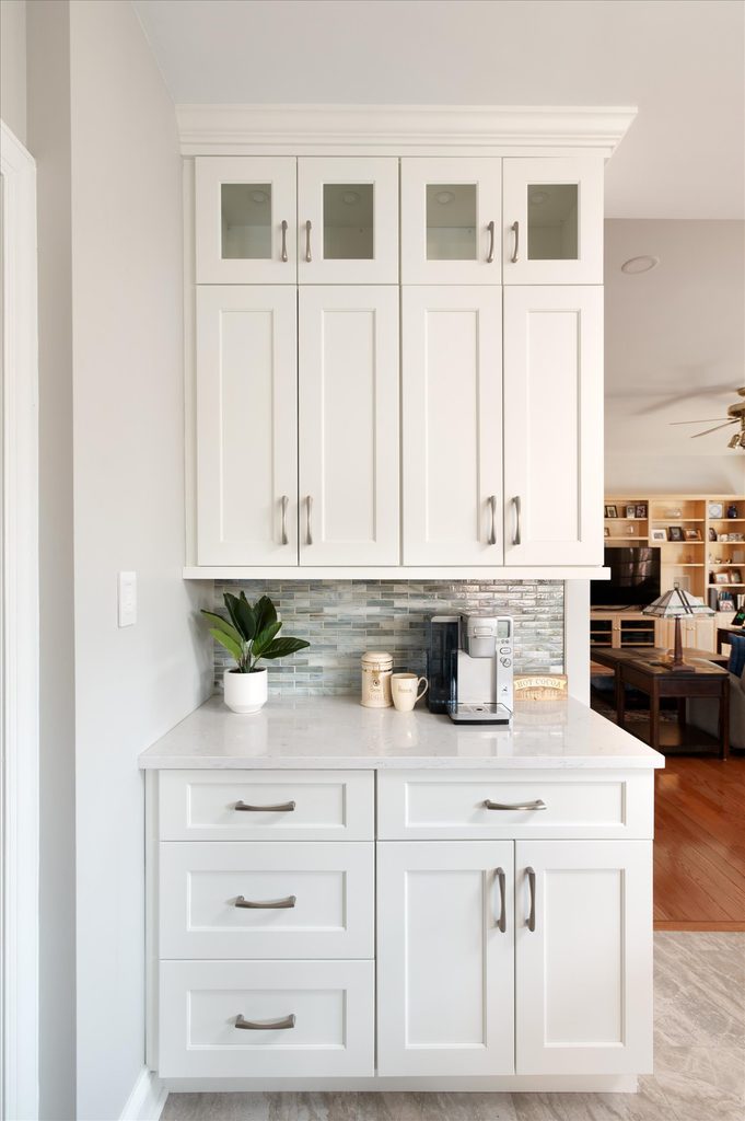 Dedicated coffee bar with stacked frosted-glass display cabinets, quartz counter, and iridescent glass mosaic backsplash