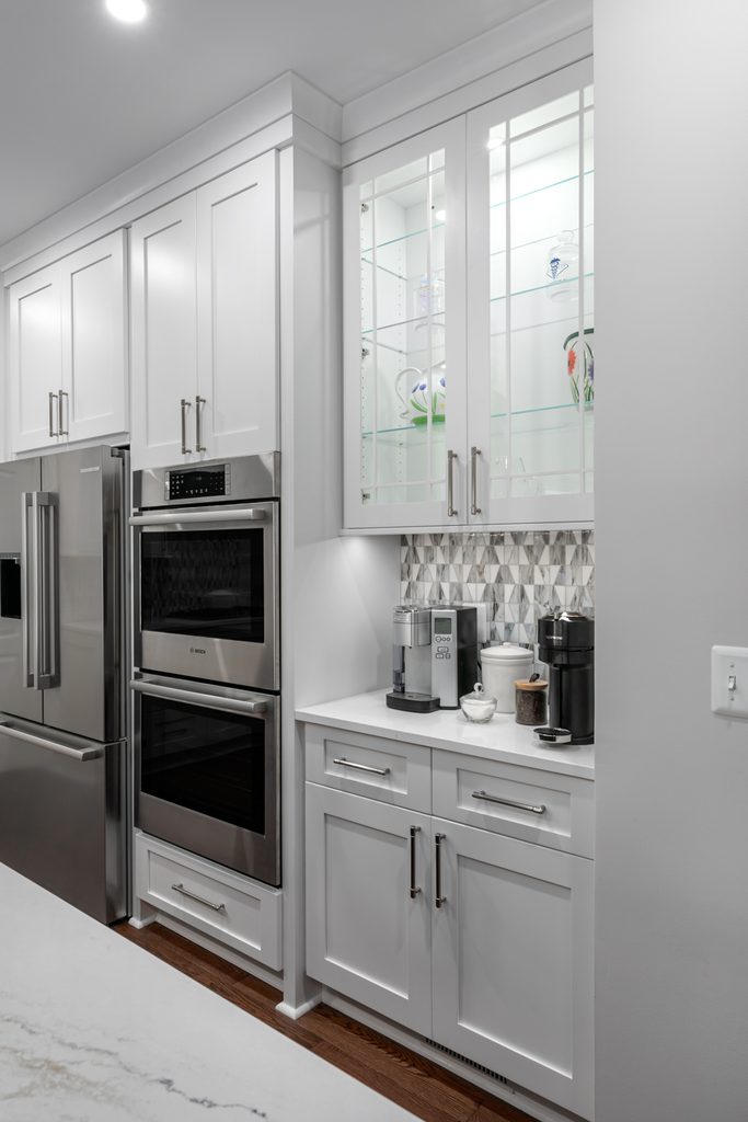 White shaker cabinets to the ceiling above warm red oak hardwood flooring