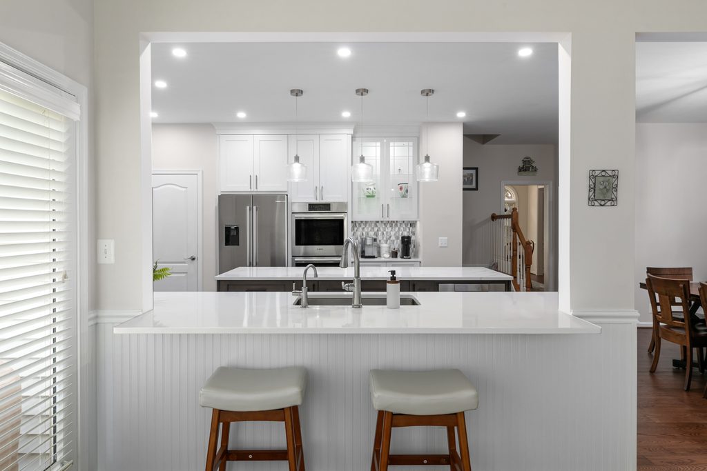 Coffee station with lit glass-front cabinets and a blue glass mosaic backsplash