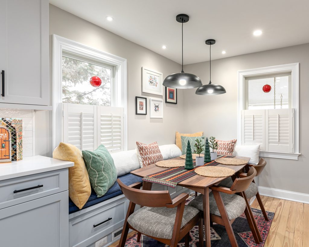 Bright two-tone kitchen with light gray upper cabinets, gray-blue base cabinets, and refinished original hardwood floors