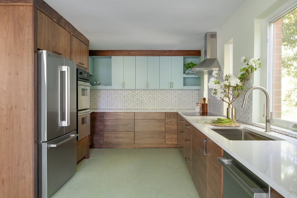 Stainless workstation sink under a new casement window in a mid century kitchen