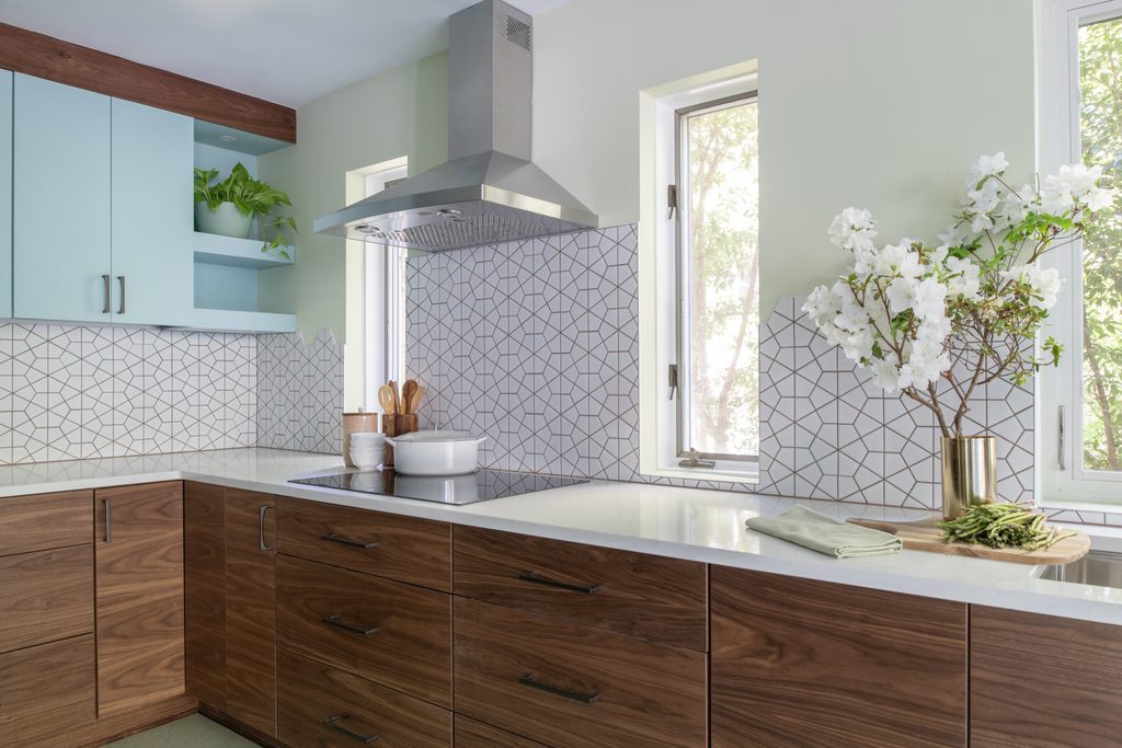 White matte porcelain mosaic backsplash with warm grout behind an induction cooktop and chimney hood