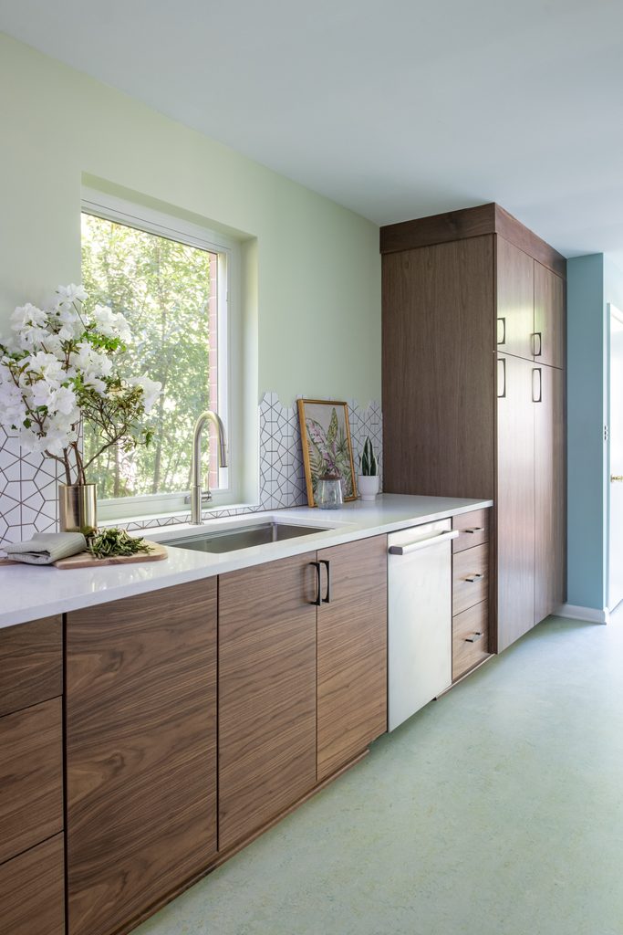 Soft blue-green painted slab cabinets beside natural walnut base cabinets