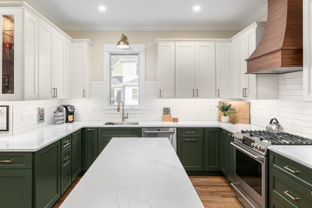 Deep green island with a marble-look quartz top and bronze cabinet pulls