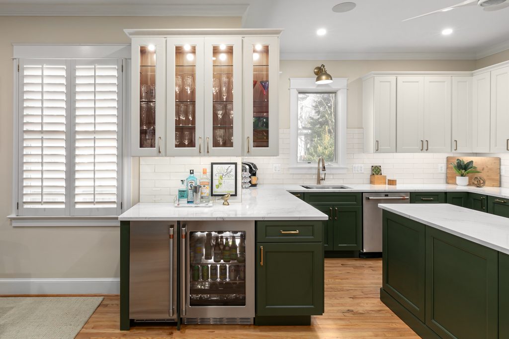 Arlington, Virginia kitchen with deep green base cabinets, soft white upper cabinets, and a walnut-stained range hood