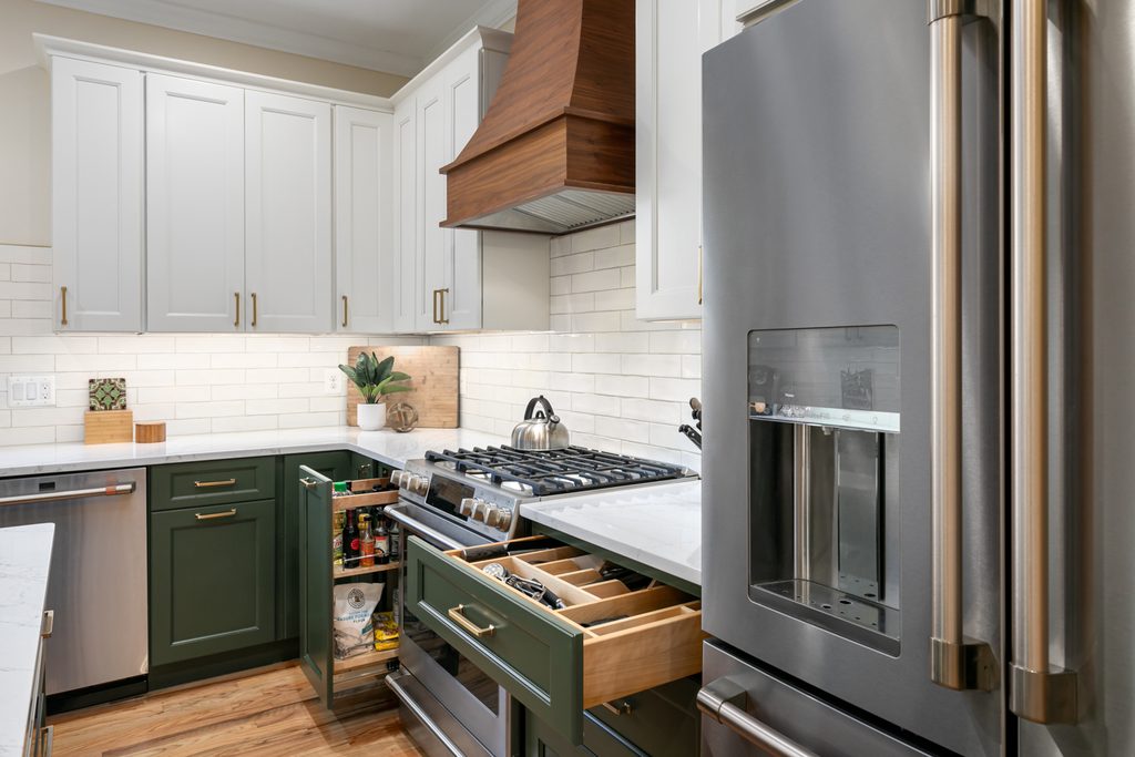 Corner beverage bar with an undercounter beverage refrigerator and ice maker in green cabinetry